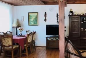 a dining room with a table and a tv at Domki na Olszynki in Okuninka