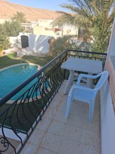 a white table and bench on a balcony with a pool at Ksour tataouine in Qaşr al Muqābilah