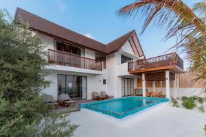 a villa with a swimming pool and a house at Meyyafushi Maldives - Premium All Inclusive in Lhaviyani Atoll