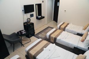 a room with three beds and a chair and a television at كنوز العمر in Mecca +36 photos