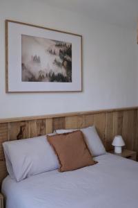 a bedroom with a white bed with a picture above it at Cozy Apartment in Pontgibaud