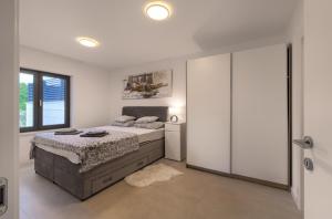 a white bedroom with a bed and a sliding glass door at Luxurious Sea-view 3BR Apartment with Private Pool-Villa Quadris-Crikvenica in Crikvenica