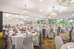 a banquet hall with white tables and chairs and chandeliers at Richland Riverfront Hotel, an Ascend Collection Hotel in Richland