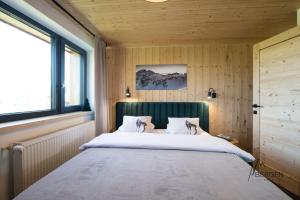 a large bed in a room with wooden walls and windows at Chata Bergen in Vysoké Tatry
