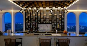 a kitchen with a bar with chairs and windows at Pantheon Hotel in Kefalos