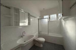 a white bathroom with a sink and a toilet and a shower at Beach house within walking distance in La Teste-de-Buch