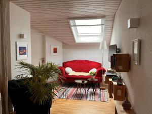 a living room with a red couch and a skylight at B&B Alpenblick in Erlinsbach