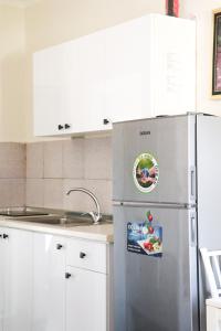 a stainless steel refrigerator in a kitchen with white cabinets at Willy Apartments in Velipojë