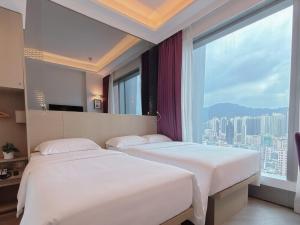 two beds in a hotel room with a large window at Starphire Hotel in Hong Kong