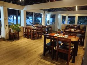 a restaurant with wooden tables and chairs and windows at Cherai Beach view Heritage in Pallipuram