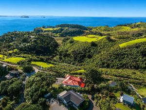 an aerial view of a house on a hill next to the ocean at Crescent Villa - Stay Waiheke in Ostend