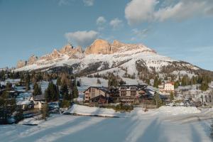 a resort in the snow with a mountain at Hotel Alpenrose in Carezza al Lago