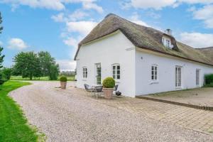 a white cottage with a thatched roof on a gravel road at HS025-Outrup-Strandvejen-31-B in Henne