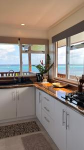 a kitchen with white cabinets and a view of the ocean at Bungalow Omati in Tahateao