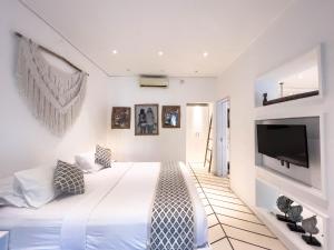 a white bedroom with a large bed and a flat screen tv at Kima Surf Camp Bali Seminyak in Seminyak +12 photos