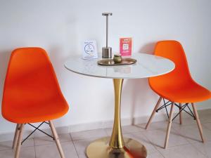 a table with two orange chairs and a white table with at Apartment Simply 203 in Gázion