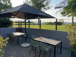 a patio with two tables and chairs under an umbrella at Neumann's Übernachtung in Plankstadt