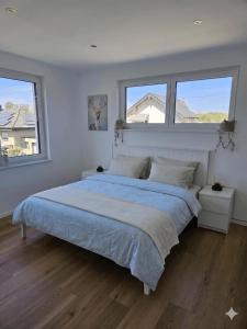 a bedroom with a large bed with two windows at Ferienwohnungen im Neubau in Ringen