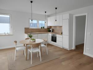 a kitchen with white cabinets and a table and chairs at Ferienwohnungen im Neubau in Ringen