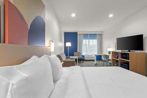 a hotel room with a bed and a flat screen tv at Spark By Hilton Missouri City in Missouri City