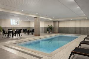 a pool in a hotel room with tables and chairs at Le Parc Gatineau, Tapestry Collection by Hilton in Gatineau