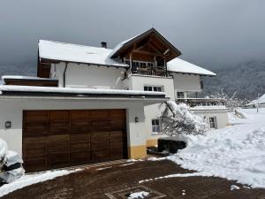 a white house with a garage in the snow at Familie Jäger in Innerbraz