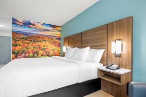 a hotel room with a bed and a phone at Clarion Pointe Springfield Southeast in Springfield