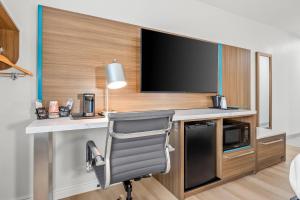 a room with a desk with a television and a chair at Clarion Pointe Springfield Southeast in Springfield