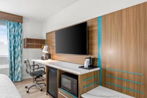 a hotel room with a desk and a flat screen tv at Clarion Pointe Springfield Southeast in Springfield