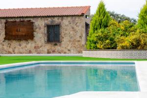 a swimming pool in front of a stone house at CR El Portezuelo Boutique Experience in Fuentelabrada de los Montes