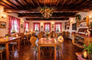 a restaurant with wooden tables and chairs and a chandelier at Penzion Sněžná Volary in Volary