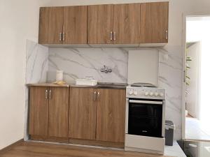 a kitchen with a stove and wooden cabinets at Stan na dan Harmonija in Nevesinje