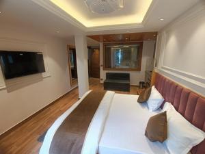 a bedroom with a large bed with a television on the wall at La Casa De Landour in Mussoorie
