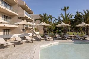 a resort with a pool and lounge chairs and umbrellas at Atlantica Thalassa Hotel in Kos