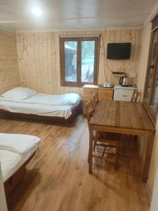 a room with two beds and a table and a tv at Leśna Ryba I Domki nad jeziorem z parkiem linowym in Jedlanka Stara