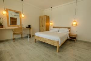 ein Schlafzimmer mit einem Bett, einem Schreibtisch und einem Spiegel in der Unterkunft Odi Beachfront Kamadhoo in Kamadhoo