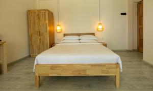 ein Schlafzimmer mit einem Bett mit weißen Laken und Kissen in der Unterkunft Odi Beachfront Kamadhoo in Kamadhoo