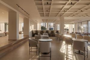 a restaurant with tables and chairs and windows at Atlantica Thalassa Hotel in Kos