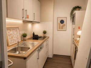 a kitchen with white cabinets and a sink at MOWO Kornwestheim in Kornwestheim