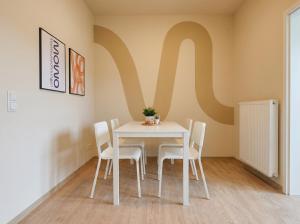 a white table and chairs with a large m on the wall at MOWO Kornwestheim in Kornwestheim