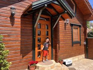 a young girl standing in the doorway of a wooden house at Petőfi 35 Vendégház in Sirok