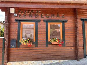 a wooden building with two windows with flowers on it at Petőfi 35 Vendégház in Sirok