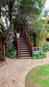 Un escalier en bois mène à un parc arboré. dans l'établissement Aark Guest Lodge, à Vanderbijlpark