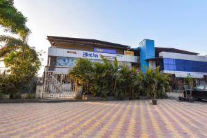 a building with palm trees in front of it at FabHotel Blue Inn I in Vagholi