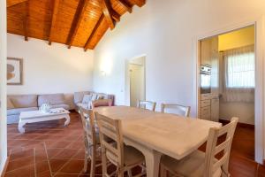 a dining room with a table and chairs and a couch at Villa Glory piscina privata in Cuile Pazzoni