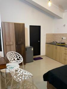 a living room with two chairs and a kitchen at Triyaah Pool View Studios Arpora, Goa in Arpora