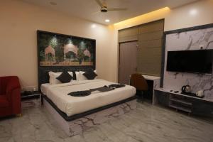 a bedroom with a large bed and a flat screen tv at Hotel Sharma Jaipur in Jaipur