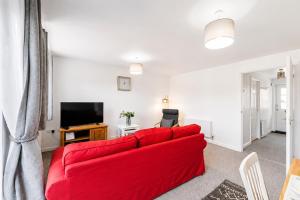 a living room with a red couch and a television at Grantham Stays - Dexter - 3BR, Sleeps 5, Parking & WIFI in Grantham