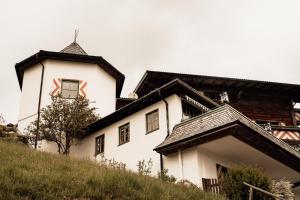 a white building on a hill with a tower at Berghotel Zugspitzblick in Zöblen +11 photos