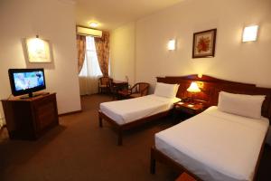a hotel room with two beds and a flat screen tv at Hotel Sapphire in Colombo
